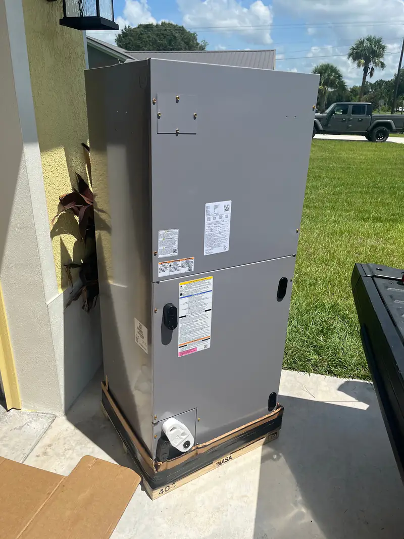 New air handler on its pallet, ready to install, under Florida palms